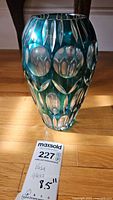 Full side view of the teal blue art glass vase showing the cut clear glass ovals and leaf shapes.