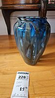 Front angle of blue and gray swirled glass vase on the floor.