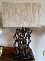 Full view of the metal art lamp showing tree branch style base and rectangular fabric shade in cream color on wooden surface.
