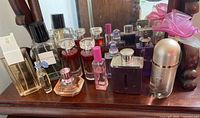Full lot of assorted perfume bottles displayed on wooden surface, various brands and sizes
