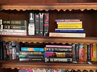Bookshelves with various books by Ayn Rand, Stephen King, Twilight series, business, and home improvement titles.