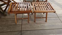 Two teak slatted foot stools side by side on outdoor deck