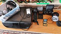 Wide view of lot contents showing printer, camera, Game Boy Advance, cartridges, headphones, charger, and keyboard