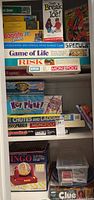 Full view of games stacked on shelves showing titles including Bingo, Risk, Monopoly, Game of Life, Clue, and others.