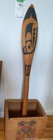Paddle standing inside wooden art box, full view of both items