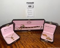 Three Juicy Couture jewelry pieces in original pink-lined cases: bracelet, necklace and charms