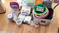 Variety of kitchen items including scales, electric grill, storage containers, plastic bowls, coffee grinder, seasoning container, and possibly other small kitchen gadgets.