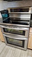 Frontal view of stainless steel KitchenAid electric stove installed between countertops showing cooktop and dual ovens
