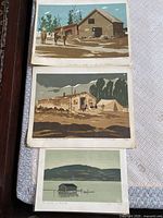 Three Weber prints showing rural and rustic scenes. Top shows barn with horses, middle shows cabin and tent, bottom shows lakeside building and dock with mountain backdrop.