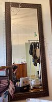 Full-length mirror with visible ornate frame hung on wall with reflection shown, illustrating size and style.