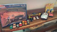 Wide view of the entire lot showing the Monogram 1955 Chevrolet Bel Air kit box and various die-cast cars including a silver Mercedes Benz model car and Hot Wheels types.