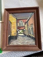 Full view of framed oil painting showing Santa Fe street scene with multiple buildings and cobblestone pathway.