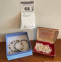 Photo showing the two boxes containing pearl necklaces and bead bracelets with a cameo cabochon, label indicating 'Pearls'
