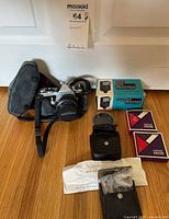 Full lot with Pentax ME camera, lens, flash unit, carrying case, and camera filters arranged on floor.