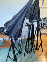 Multiple folded umbrella reflectors and light stands grouped together, showing carrying bags labeled with 'Photo Studio'