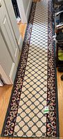 Full length of the narrow runner rug laid down a hallway floor showing the full design and border.