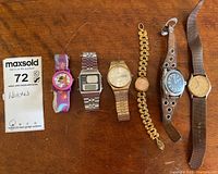 Overview of six wristwatches on wooden surface