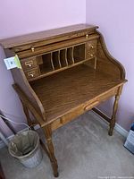 Front angled view showing the roll-top desk with small drawers, compartments, and turned legs.