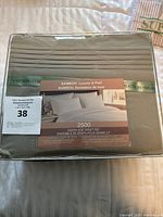 Packaged queen size bamboo sheet set in neutral taupe color with visible label and branding.