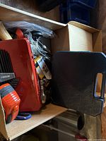 Overview of box with red metal toolbox, hand tools and accessories inside
