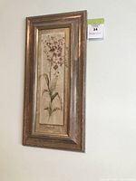 Photo of entire framed orchid floral art print hanging on wall, showing full frame and botanical illustration.