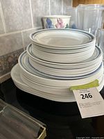 Stack of white Corelle plates with a thin blue line around the rim, various sizes visible from side angle.