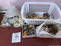 Overview of all jewelry items including plastic basket, box, pouch, and bag with mixed costume jewelry.