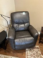 Front view of dark gray leather recliner in corner of room