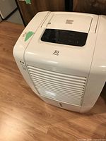 Front and side angle of the white Kenmore dehumidifier on wood floor, showing the 50 pints label and electronic control panel on top.