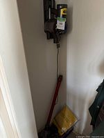 Main vacuum unit mounted on wall with charger dock, red wand and coiled power cable