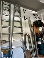 Photo showing the large aluminium extension ladder leaning against a wall, alongside other tools and equipment.