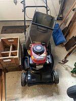 Front-angle view showing Honda engine housing, cutting deck and attached grass bag