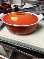 Oval Le Creuset roaster pot with lid in orange gradient enamel on white counter.