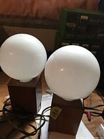 Pair of MCM style lamps with wood rectangular bases and white globe glass shades, front angle view showing both lamps and cords.