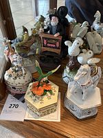 Overview of lot showing hummingbird music box, organ grinder figurine, pony musical box, carousel horse, and other bird decorative pieces.