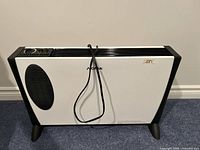 Front view of white and black Noma electric heater with power cord wrapped around the front and black vent on the side.