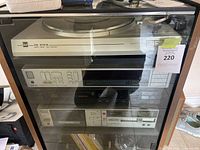 Front view of the vintage audio cabinet showing the Dual CS 616 Q turntable on top and three additional components stacked below inside a glass-front wooden cabinet.