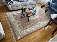Full view of the Oriental rug in a living room setting under a glass coffee table with beige and mauve floral design.