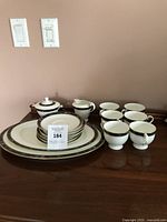 Full view of the tea set showing 6 tea cups, saucers, creamer, sugar bowl, and 2 platters on a wood surface.