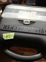 Close-up of Black & Decker palm sander carrying case with lid partially transparent showing embossed brand name.