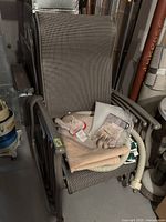 Stacked set of six dark metal patio chairs with mesh seating and backs, some items placed on top of the top chair.