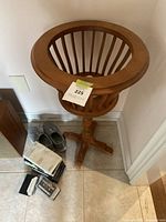 Wooden plant stand displayed in corner on tile floor, showing circular basket and pedestal base.