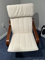 Front view of the white cushioned pong chair with wooden curved armrests.