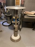 Full front view of the propane patio heater showing the body with control knob, metal grill, and reflector top