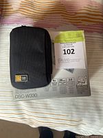 Black fabric carrying case and original Sony Cyber-shot DSC-W330 box with lot tag visible