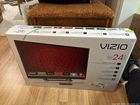 Photo of the Vizio 24-inch E-Series Smart TV box showing the front with image of the TV and various streaming app logos.