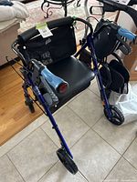 Full front and side view of blue rollator walker showing seat, brakes, wheels