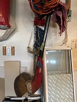 Red and black Toro gas weed wacker leaning against a wall, showing the curved shaft, handle, and trimmer head with guard.