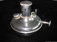 Side view of antique camp burner showing overall shape and components