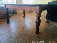 Side view of walnut dining table showing turned legs and casters